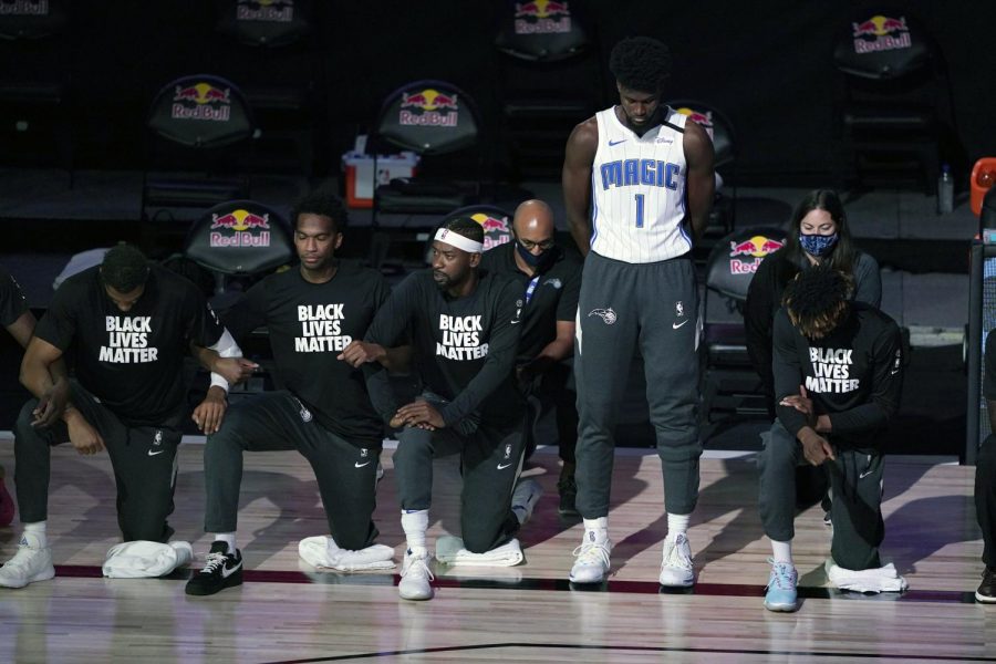 Jonathan Isaac decides to stand during the National Anthem and where his Orlando Magic jersey. Image from AP News.com