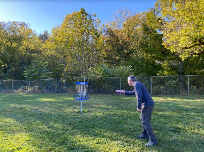 Disc golf player sets up his shot to make it in the basket.