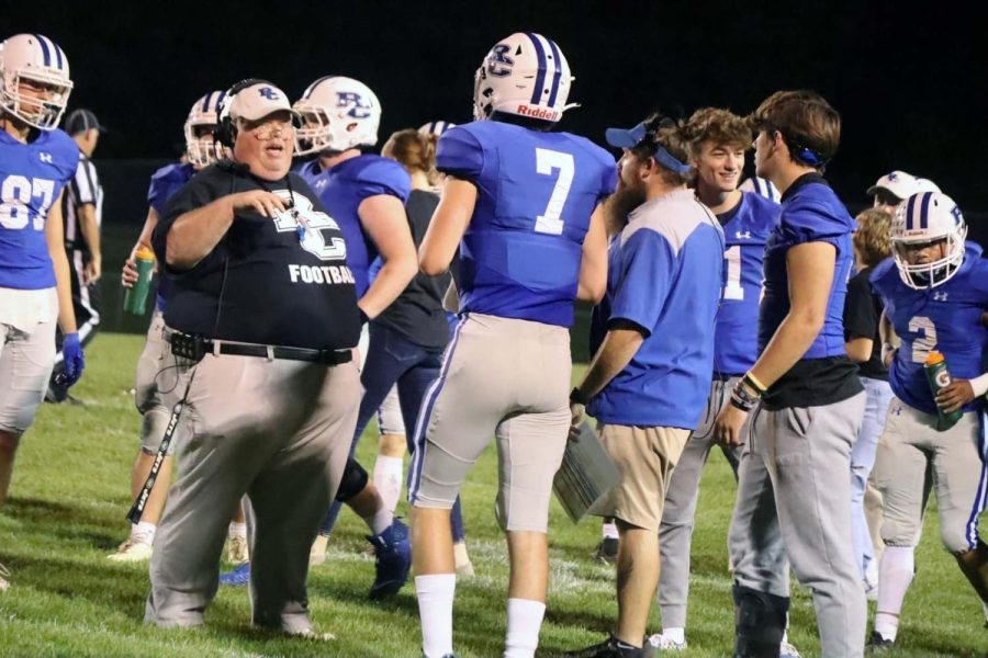 Coach Mark Poston meets with Quarterback, Miller Jay during a game.