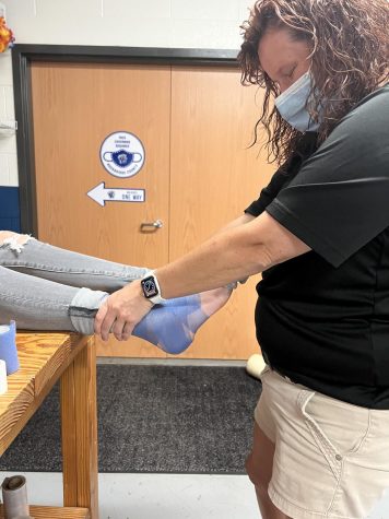 Athletic trainer Ms. Courtney taping an athlete in the training room. 