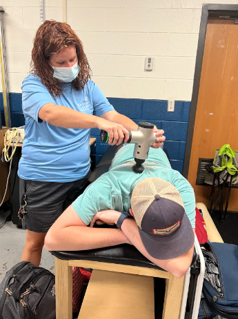 Simpkins uses a massage gun on Junior baseball player, Thomas Armstrong, before workouts. 