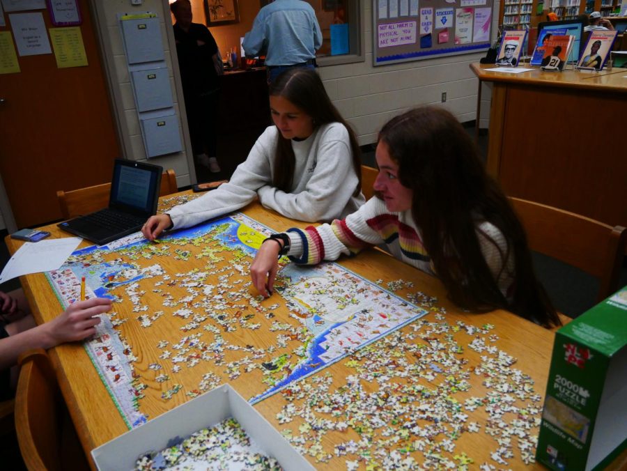 Seniors Sophia Fafatas and Grace Rolon working on a puzzle in the library. 