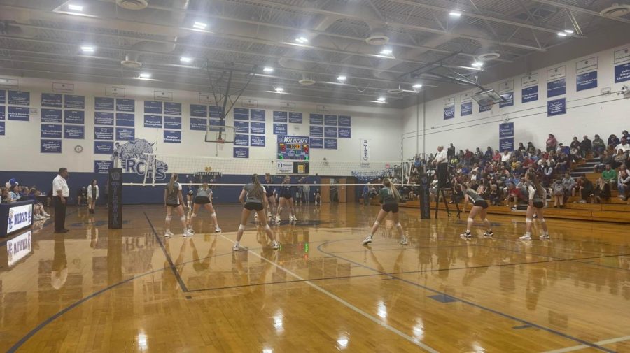 Volleyball players set up on the court to get ready to play.