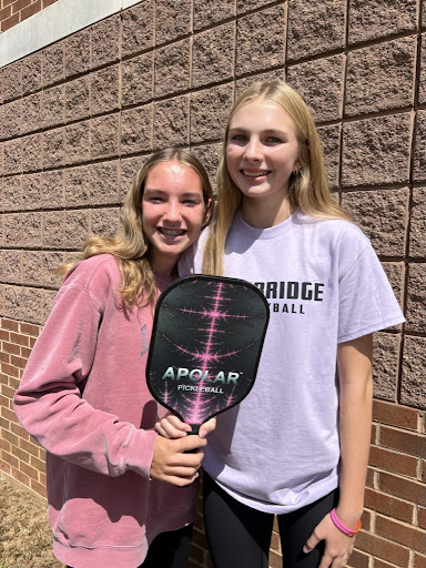 Freshmen Anna Nye and Geneva Snyder pose with a pickleball paddle. 
