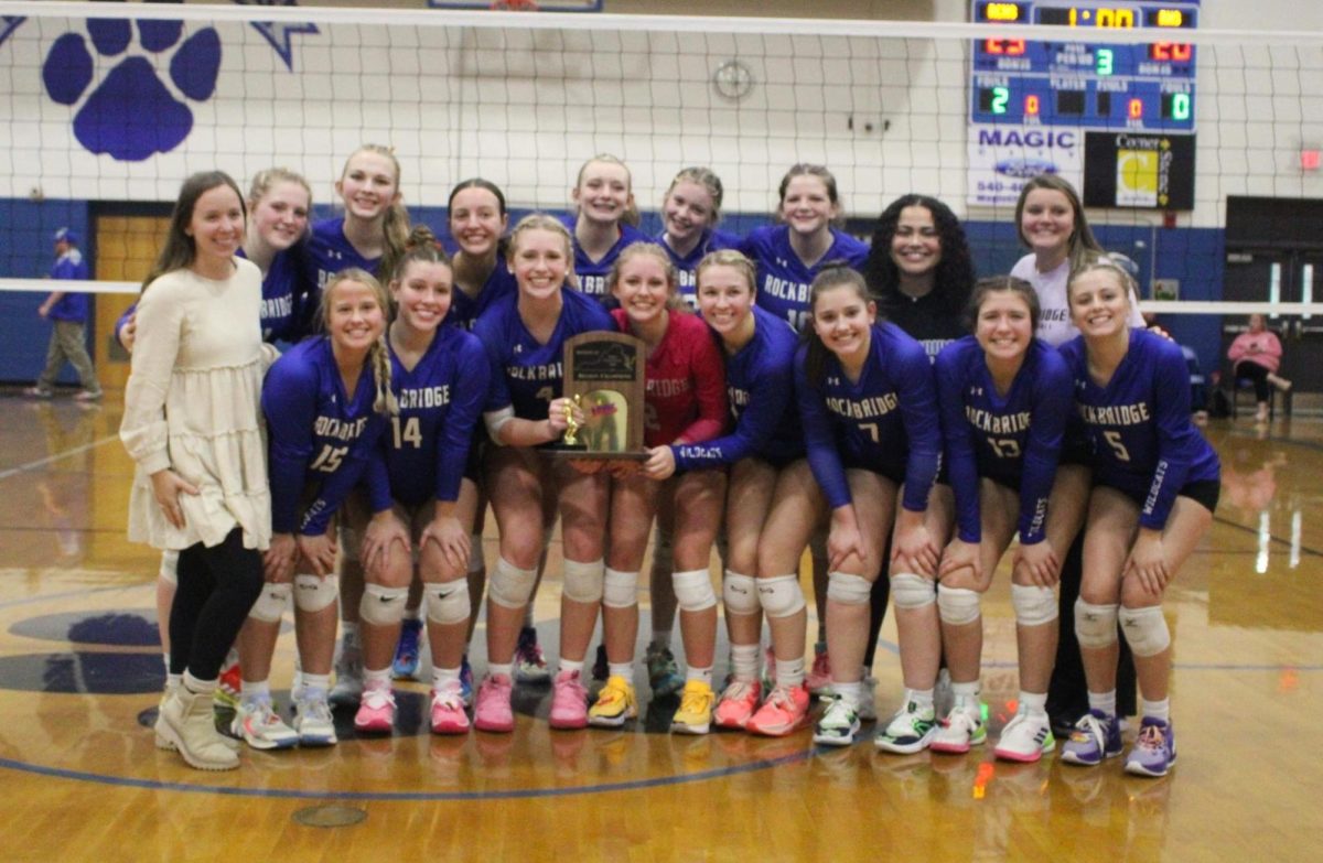 Volleyball girls pose with their trophy after their game. 