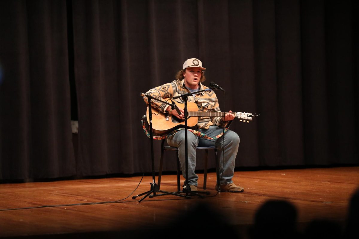 Daniel Grimm playing the guitar and singing I Remember Everything by Zach Bryan at the Talent Show.