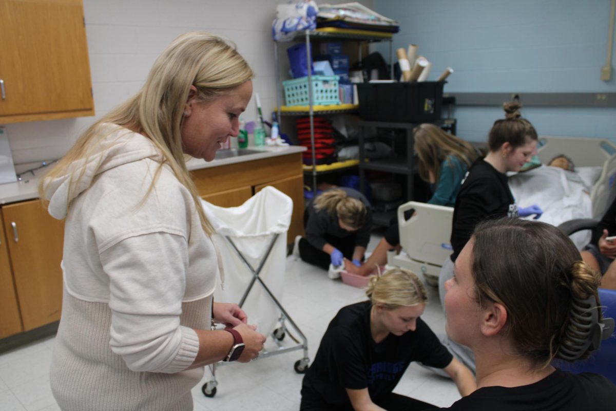 Heather Higgins helps students practice nurse aid skills.