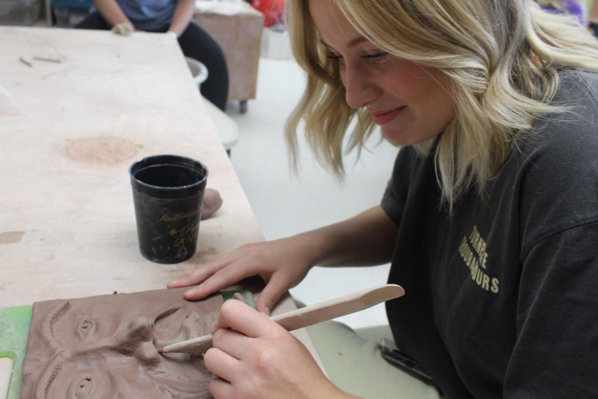 Senior Elizabeth McCormick adds details to her tile.