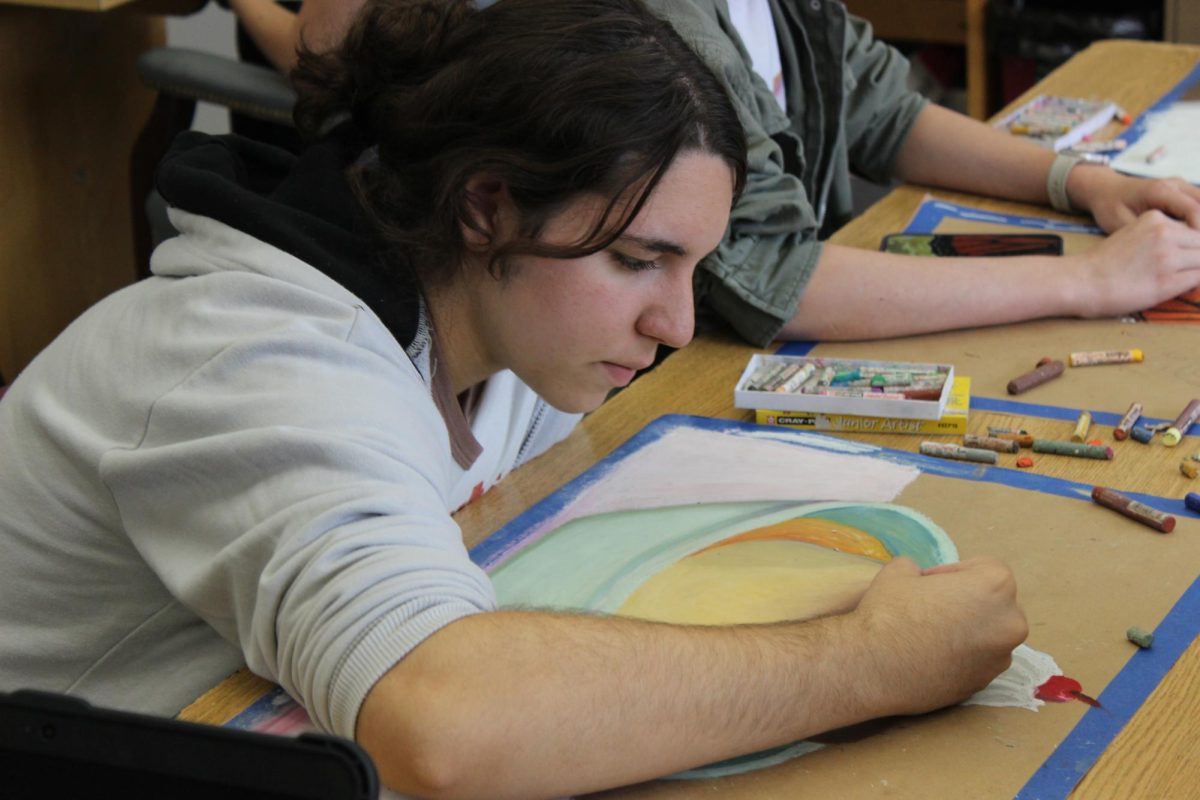 Junior Madison Lipscomb works on an oil pastel drawing. 