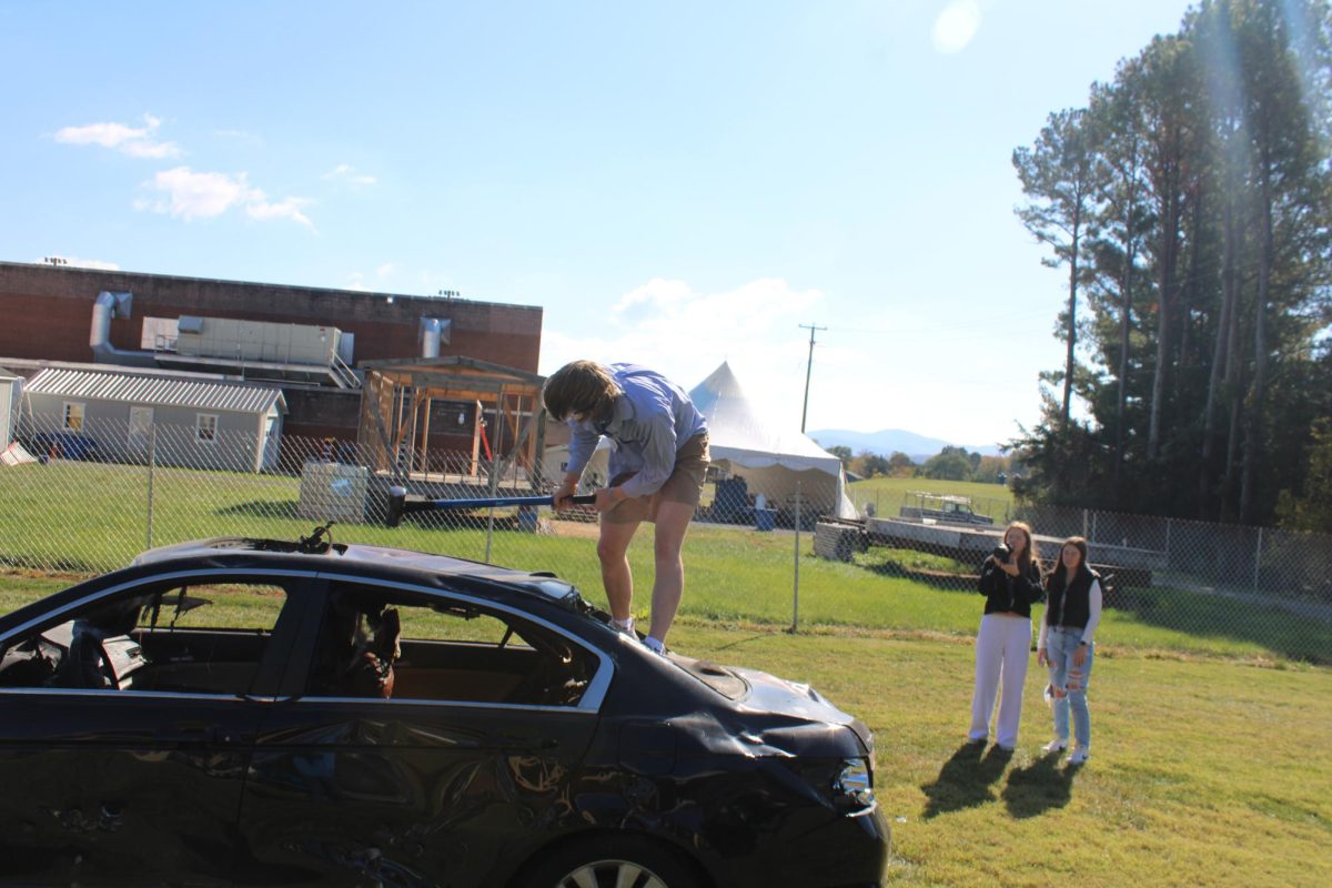 Sophomore Chase Potter hits the car with a sledgehammer.