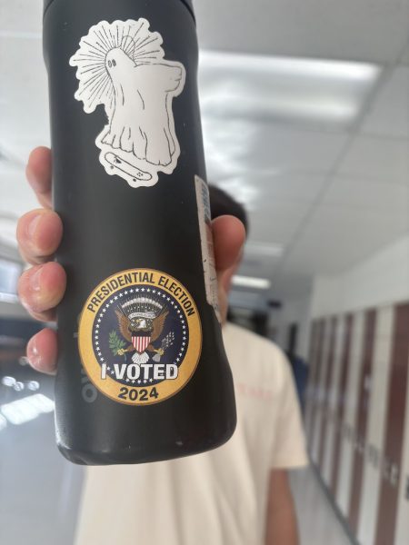 A student holds up his "I Voted" sticker. 