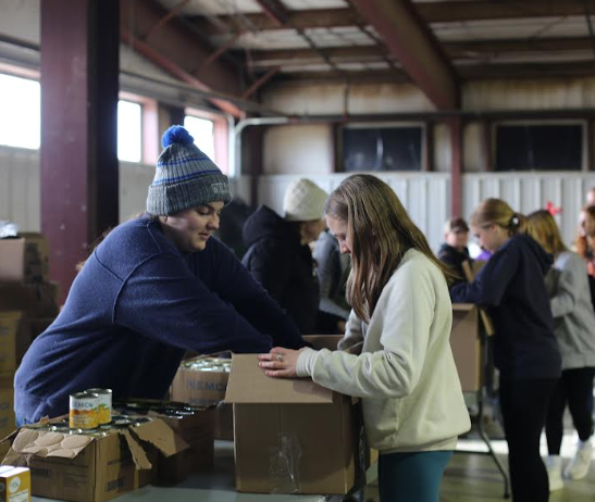 RCHS student helps pass out food in the assembly line.