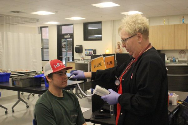 Junior Daniel Reed gets his temperature taken by a Red Cross staff member prior to giving blood. 
