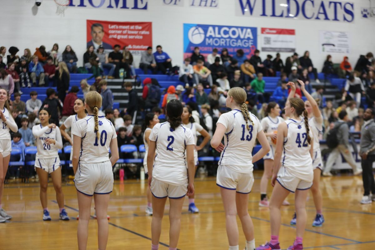 Girls basketball team lines up on the free throw line for warm ups. 