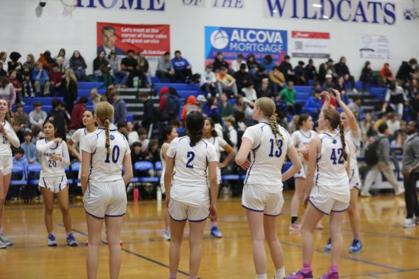 Girls basketball team lines up on the free throw line for warm ups. 