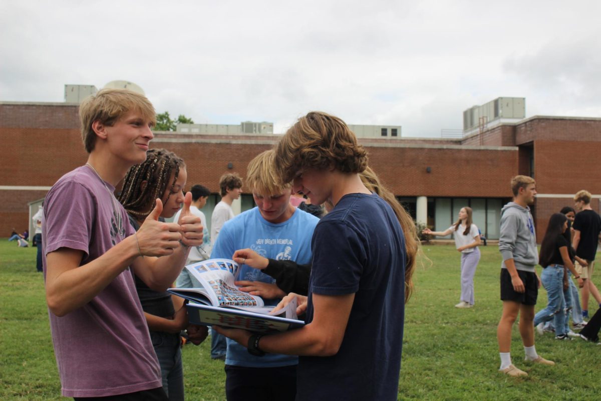 A group of Juniors look at the yearbook.