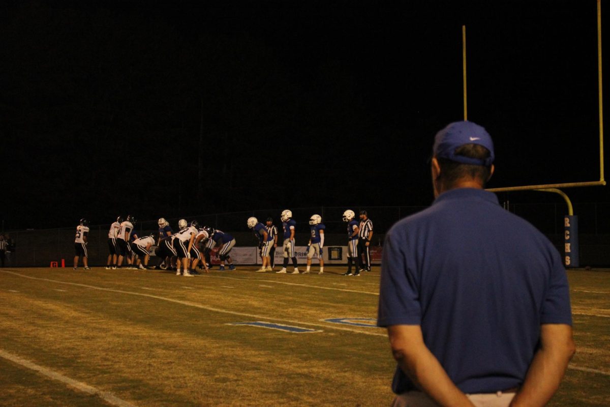 Wildcats assistant football coach looks on as the defense sets up. 