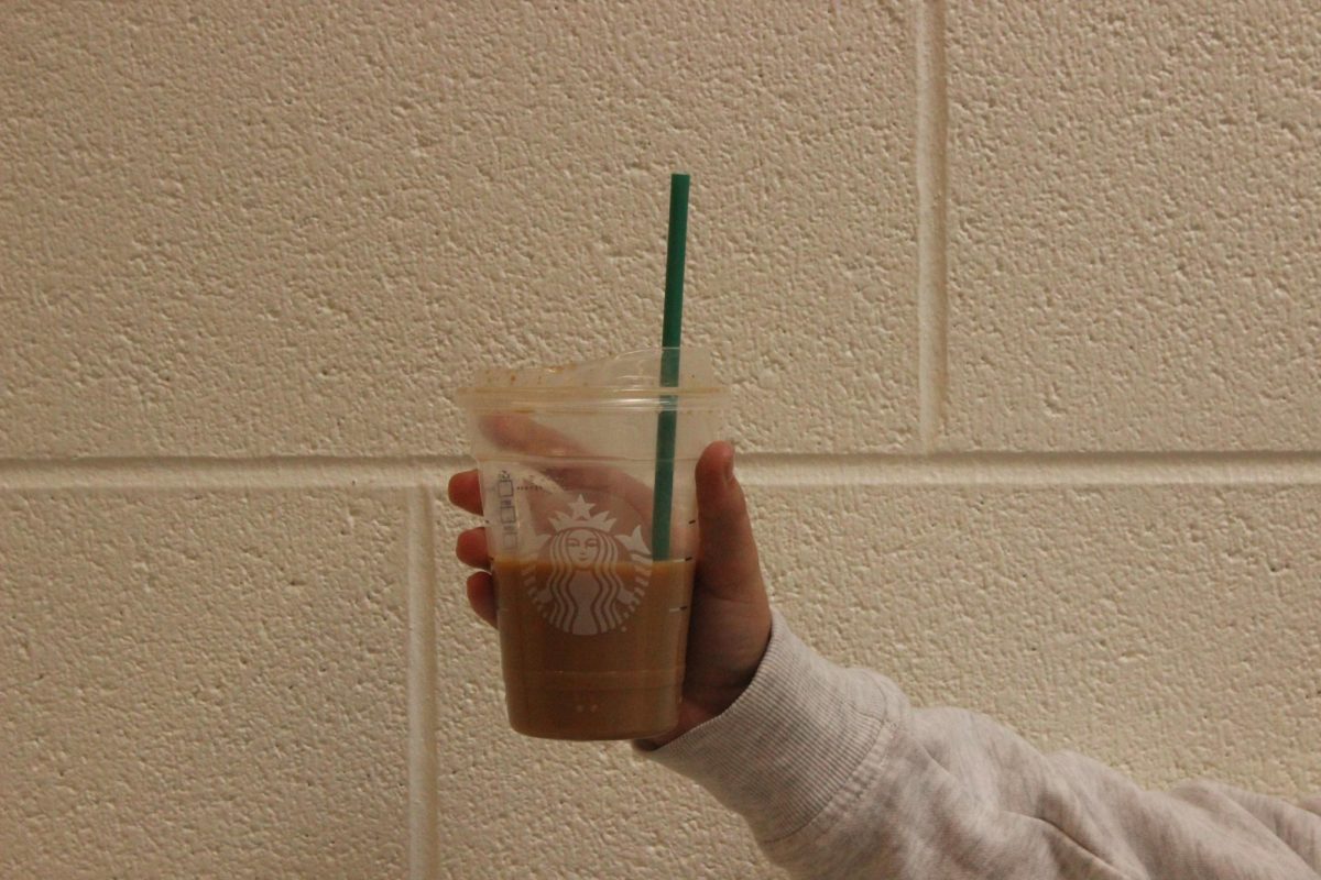Student holding a Starbucks Fall Pumpkin Spice Latte. 

