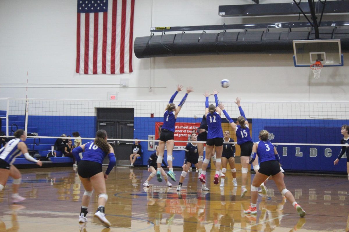 Senior Jada Hamilton, junior Emmy Duff, and junior Emma Johnson all jump up for a block.