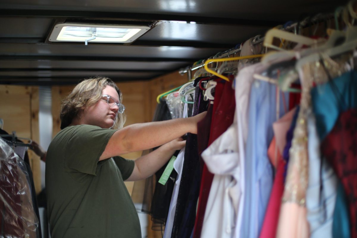Junior Food for Thought intern Joshua Hughes looks through dresses from the Cinderella Project trailer. 
