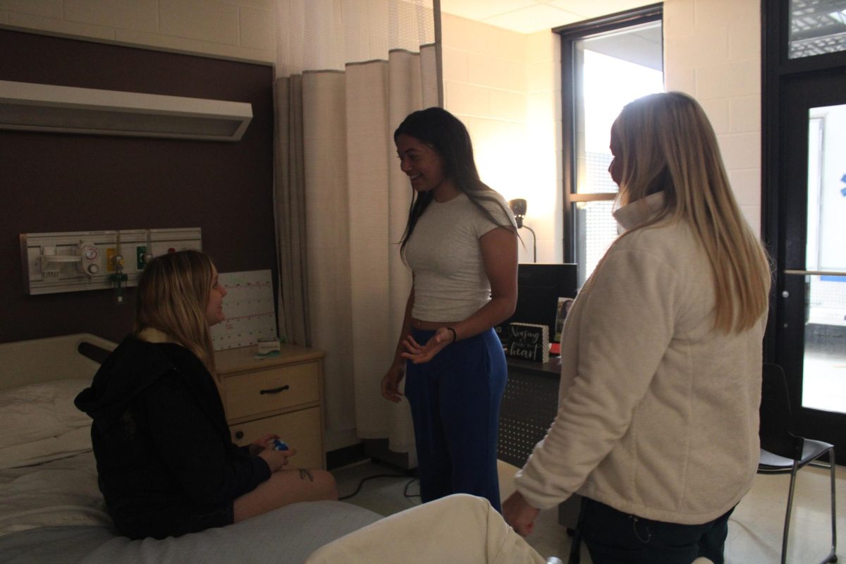 Nurse aide instructor Heather Higgins assists sophomore Ariana Mitchell and junior Savannah Harrison with a skill.