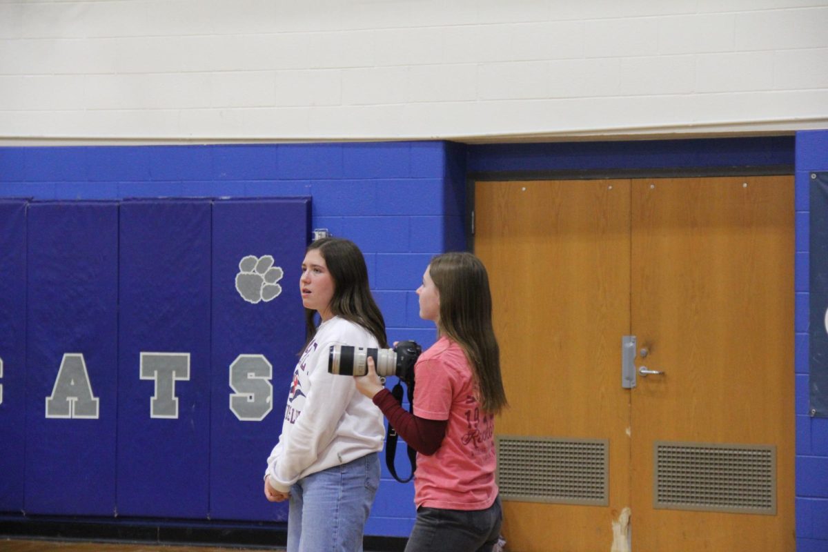 Junior Adrianna Grue and Sophomore Addie Brown stand on the sidelines.