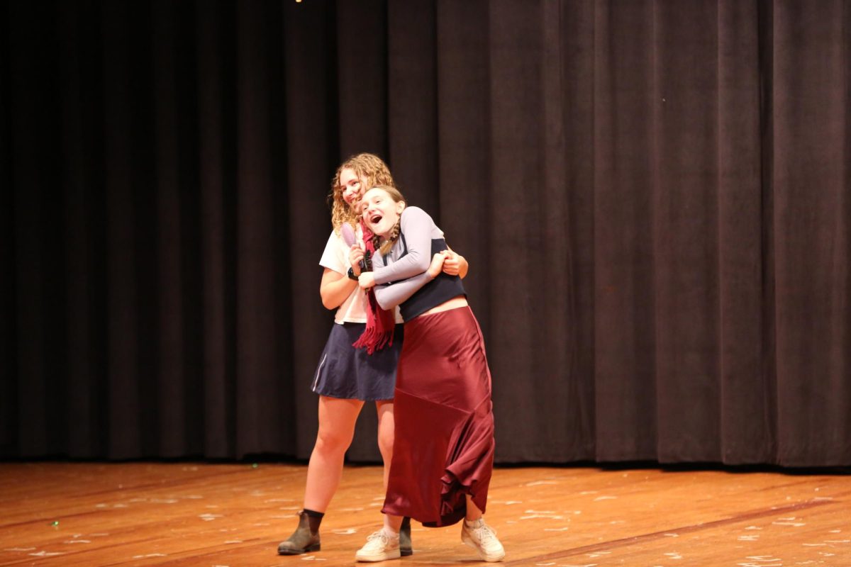 Seniors Ella Brown and Casandra Silver hug each other during the song "Love is an Open Door"