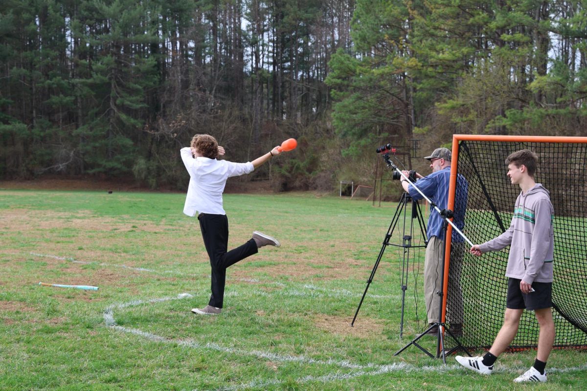 Senior River Jenkins takes a swing while senior Noah Alexander films.